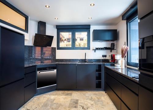 - une cuisine avec des placards noirs et un évier dans l'établissement Le Montaska - Chalet 15 personnes - La Plagne, à La Plagne Tarentaise