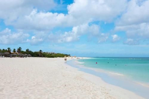 a beach with people swimming in the ocean at Beachfront- Eagle Beach- Top View 1BR condo - P514 in Palm-Eagle Beach