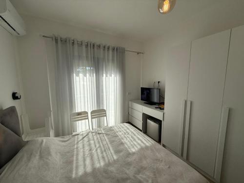 a white bedroom with a bed and a television at sunset room in Golem