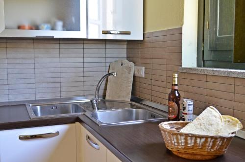 fregadero de cocina con cesta y botella de vino en Casa Vacanza Arbatax, en Àrbatax