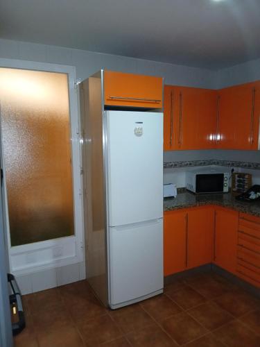 a white refrigerator in a kitchen with orange cabinets at Bonito piso de 2 habitaciones in Híjar