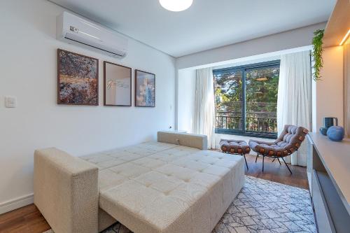 a bedroom with a large bed and a window at Dona Ella 202 - Apê NOVO no Centro de Gramado in Gramado