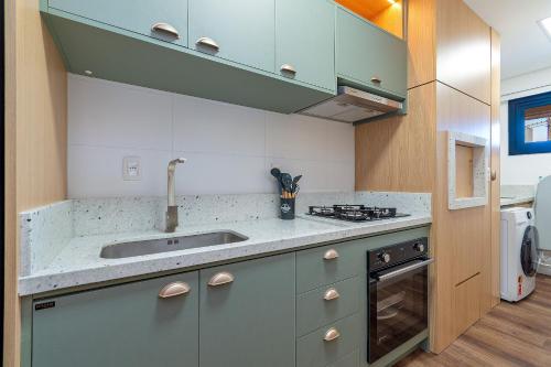 a kitchen with a sink and a stove top oven at Dona Ella 202 - Apê NOVO no Centro de Gramado in Gramado