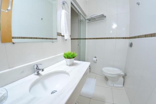 ein weißes Bad mit einem Waschbecken und einem WC in der Unterkunft Turis Hotel in Passo Fundo