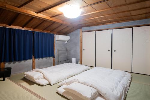 a bedroom with two beds in a room with wooden ceilings at kumihimo kobe in Wada