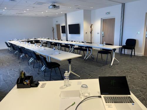 a large conference room with a long table and a laptop at Holiday Inn Dijon Sud - Longvic by IHG in Dijon