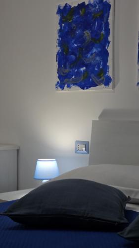 a bed with a black pillow and a blue painting at 41 Parallelo - Comfort rooms in Bari