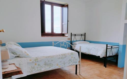 two beds in a room with a window at Alba dei due Soli, Appartamenti in Ceresole