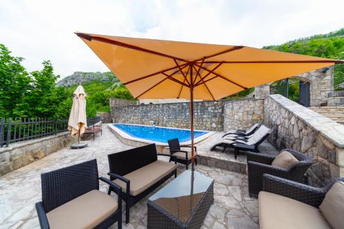 a patio with an umbrella and a swimming pool at Blake's Villa in Budva