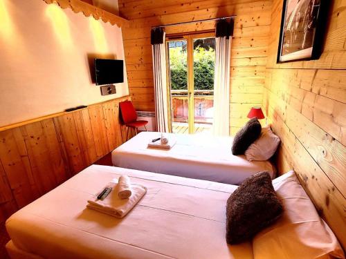 une chambre avec 2 lits et une télévision dans une cabine dans l'établissement Duplex lumineux avec terrasse et balcon, proche centre et pistes, parking, WiFi - FR-1-598-71, aux Gets