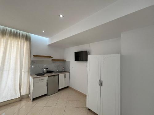 a kitchen with white cabinets and a white refrigerator at Guesthouse Butrinti in Ksamil