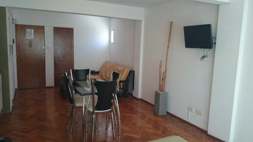 a room with a table and chairs and a television at Temporarios Peatonal in Rosario