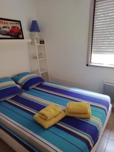 - un lit avec 2 serviettes jaunes au-dessus dans l'établissement Très beau T2 à100m du bord de mer, à La Ciotat