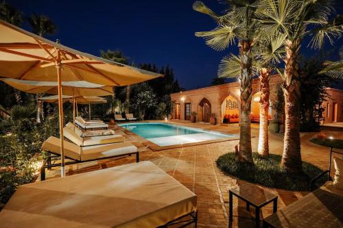a house with a swimming pool with chairs and an umbrella at Villa Sophia in Azib Oulad Lâdem