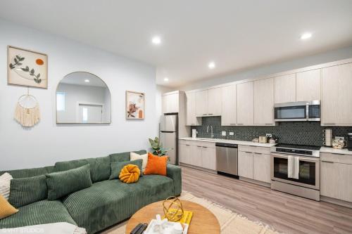 a living room with a green couch and a kitchen at Eco Stay by UChicago, Lakefront & Hyde Park! in Chicago