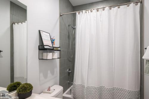 a bathroom with a shower curtain and a toilet at Eco Stay by UChicago, Lakefront & Hyde Park! in Chicago