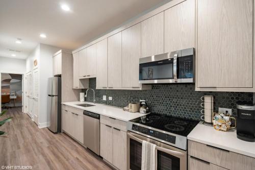 a kitchen with white cabinets and a stove top oven at Eco Stay by UChicago, Lakefront & Hyde Park! in Chicago