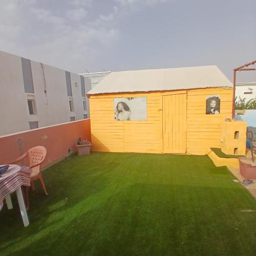 a small yellow building with two dogs in the windows at Auberge Triskell in Nouakchott