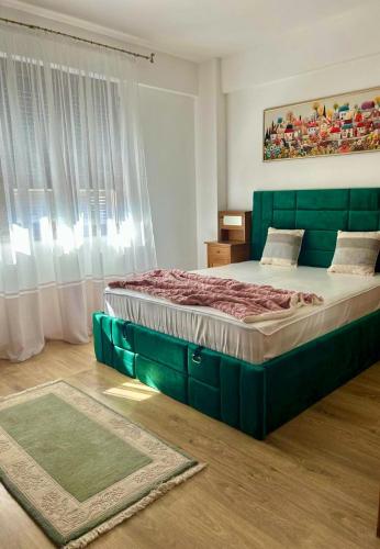 a bedroom with a large bed with a green headboard at Clabucet View Apartment in Predeal