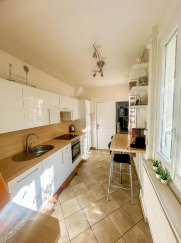 - une cuisine avec des placards blancs, un évier et une table dans l'établissement La ContrEscarpe - 4 couchages - Cour PRiVÉE - Secteur GARE CENTRE, à Amiens