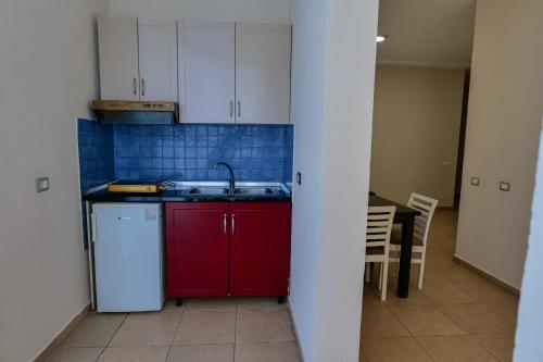 a kitchen with red cabinets and a sink and a table at Blu Apart Hotel Durres in Durrës