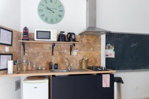 a kitchen with a sink and a clock on the wall at Terre Luberon in Pertuis