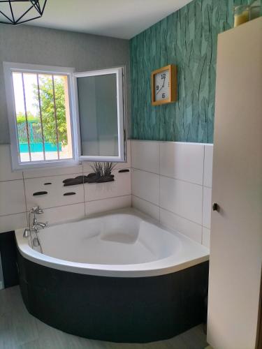 une grande baignoire dans une salle de bain avec une fenêtre dans l'établissement Maison circuit 24 heures du Mans, à Teloché