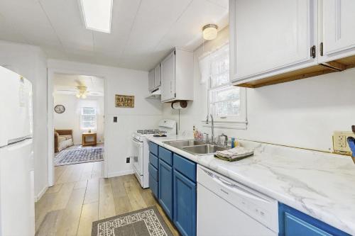 una cocina blanca con armarios azules y fregadero en Voyagers Cabin, en Eagle River