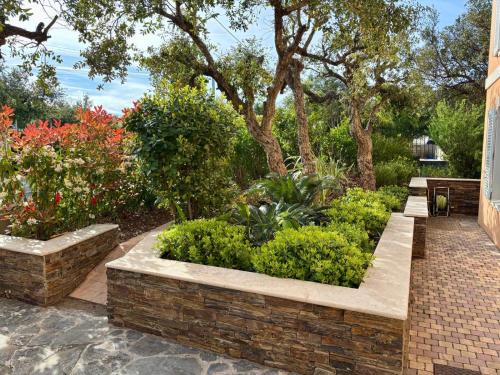 un jardin avec un mur en briques et quelques buissons dans l'établissement La Bastide, à Fréjus