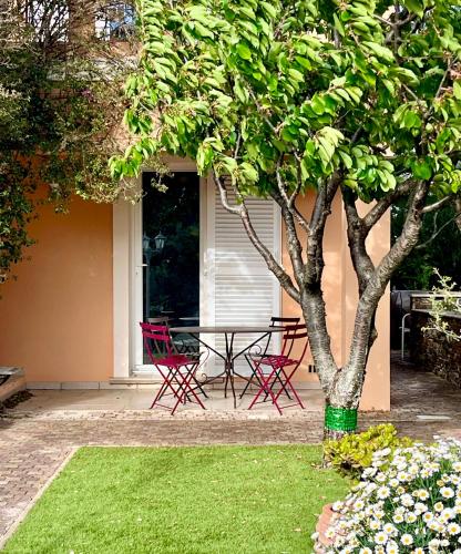 une terrasse avec une table et des chaises à côté d'un arbre dans l'établissement La Bastide, à Fréjus