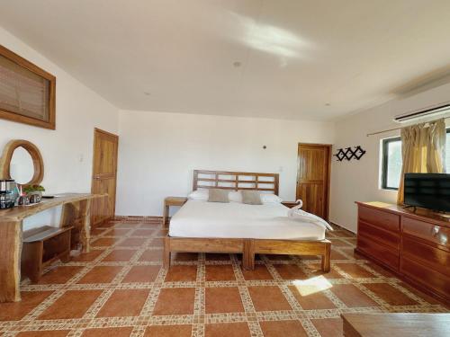 a bedroom with a bed and a flat screen tv at Hotel El Perico Marinero in Río Lagartos