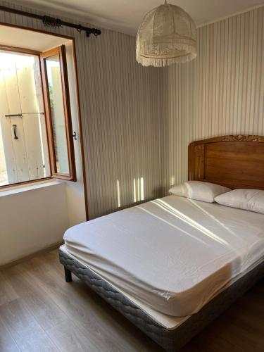 une chambre avec un grand lit avec une grande fenêtre dans l'établissement maison au coeur du village, à Ruoms