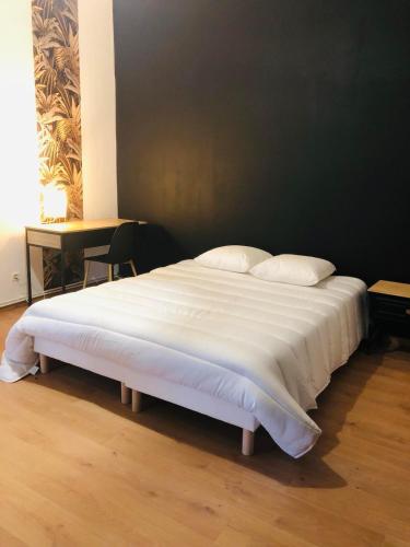 un grand lit blanc avec des draps et des oreillers blancs dans l'établissement Maison atypique au pied de l'Eglise St Géry, à Cambrai