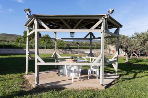 a gazebo with a table in the grass at Theros, garden and sea in Mesimvría