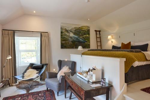 a bedroom with a bed and a desk and chairs at Monachyle Mhor Hotel in Lochearnhead