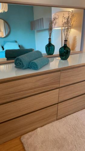 une commode avec deux vases verts dessus dans l'établissement Superbe Chambre avec vue et salle d eau privative dans duplex de 140m2 - proche CHU Clermont, à Beaumont