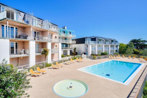 - une piscine en face d'un bâtiment avec des chaises dans l'établissement Le Phare de Trescadec - maeva Home - 2 Pièces 4 Personnes Sélection MAE-3559, à Audierne