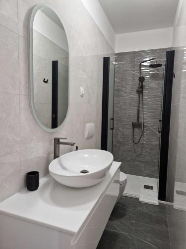 a white bathroom with a sink and a shower at Apartmani Kordić in Barbat na Rabu