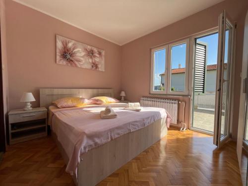a bedroom with a bed and a large window at Apartmani Kordić in Barbat na Rabu