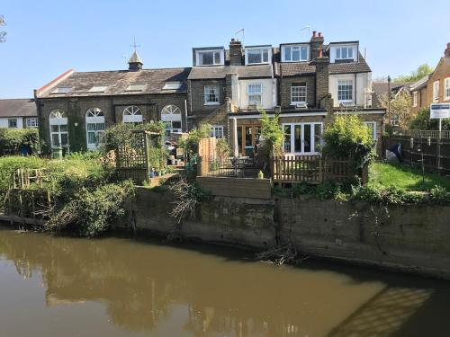 a large house next to a body of water at Lovely riverside cottage, Weybridge, Surrey in Weybridge