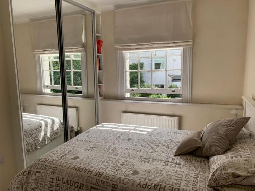 a bedroom with a bed and two windows at Lovely riverside cottage, Weybridge, Surrey in Weybridge