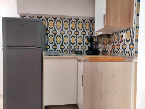 a kitchen with a refrigerator and a tile wall at Casa de Férias Palmeira in Faro