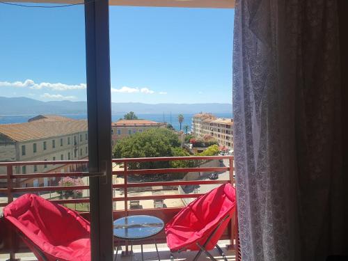 d'un balcon avec des chaises rouges et une vue sur la ville. dans l'établissement L Essentiel, à Ajaccio