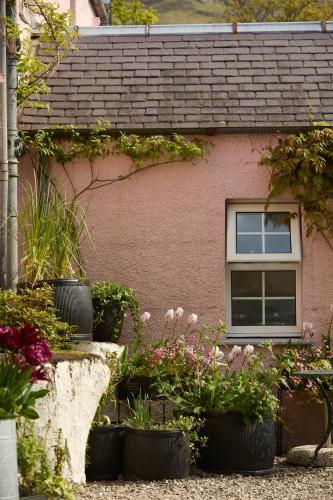 a house with pots of flowers in front of it at Monachyle Mhor Hotel in Lochearnhead