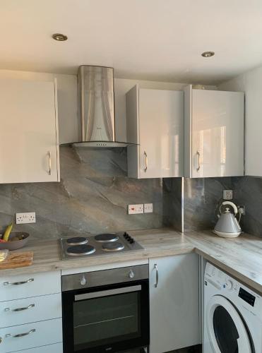 a kitchen with white cabinets and a stove top oven at Glastonbury town centre modern apartment in Glastonbury
