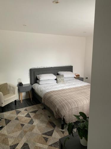 a bedroom with a large bed and a chair at Glastonbury town centre modern apartment in Glastonbury