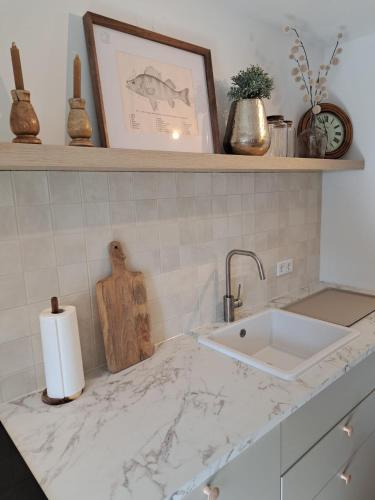 a kitchen counter with a sink and a shelf at Ferienwohnung auf dem Mühlenhof in Glinstedt
