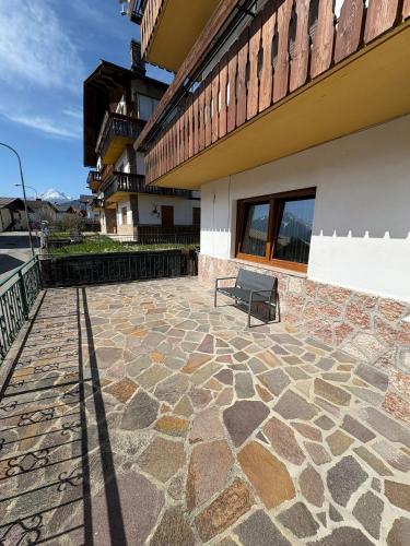 a bench sitting on a stone patio next to a building at RomAnna in Domegge di Cadore