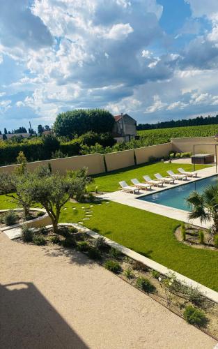 une image d'un jardin avec une piscine et des chaises longues dans l'établissement Le Mas de Sandre, en campagne, à Châteaurenard