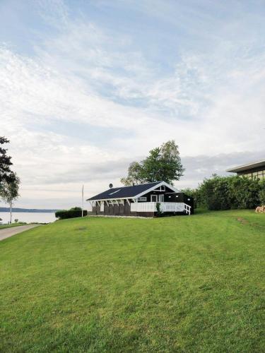 a black and white house with a large grass field at Holiday Home With Fjord Views In Hjarbæk in Løgstrup